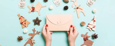 Bayram süslemelerinden yapılmış mavi arka planda bir zarf tutan kadının üst görüntüsü. Noel zamanı konsepti.