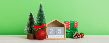 25 december. Christmas composition on colored background with a wooden calendar, with a gift box, toys, bauble copy space.