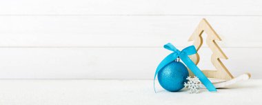 Christmas ball with decorative wooden tree on colored background. decoration bauble with ribbon bow with copy space.