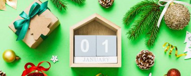 Christmas calendar 1 january. Christmas gift, fir branches, pine cones. Flat lay, top view. New Year decorations on a colored background.