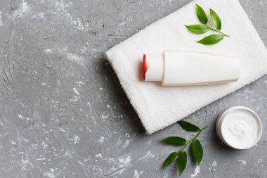 Kozmetik şampuan şişesi renkli bir masada havluyla birlikte. Banyo arka planı, el ve vücut bakımı için tuvalet aksesuarları..