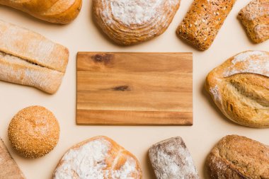 Minimalist ahşap kesim tahtası ev yapımı ekmek çeşitlerinin arka planında boş bir model. Arka plan olarak farklı taze ekmek türleri, metin veya tasarım için boşluk ile üst görünüm.