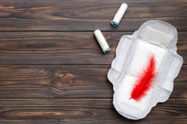 Kadın pedleri ve tamponları. Pembe ve menekşe arka planda izole edilmiş bir arka planda hijyenik pedlerin yanında uzanıyor. Kadın hijyeni ve adet dönemi konsepti.