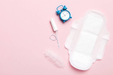 Alarm saatini hijyenik kadın tamponları ve regl pedleri ile çalıyor. Tıbbi konsept kadın kritik günler ve regl dönemi. Kadın günlük hijyen. Boşluğu kopyala.