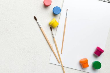 Albüm sayfaları, boyalar, kalemler, renkli arka planda fırçalar. Boşluğu olan üst görünüm. Yaratıcılık için işyeri. ev öğretmenliği kavramı çizimi.