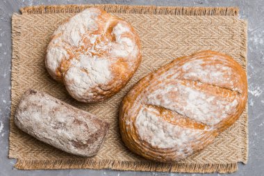 Kırsal masa manzaralı peçeteli taze pişmiş ekmek çeşitleri. Sağlıklı mayasız ekmek. Fransız ekmeği.