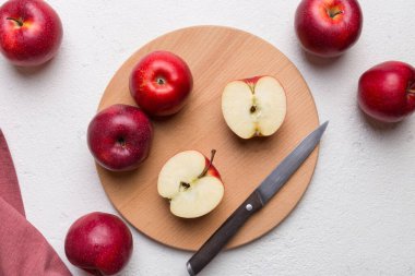 Yeşil yapraklı taze kırmızı elmalar. Bıçakla kesme tahtası. Üst görünüm.
