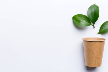 Yeşil yapraklı sıfır atık bardak, çevre dostu, tek kullanımlık, karton, çevre dostu kahve fincanı. Kopyalama alanı ile en üstte görünüm.