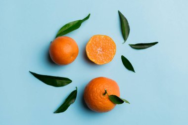 Renkli arkaplanda yeşil yaprakları, üst görünümü, metin için alanı olan bir sürü olgun mandalina..