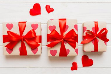 Top view photo of valentine day decorations gift box with red ribbon bow on colored background. Holiday gift boxes with top view.