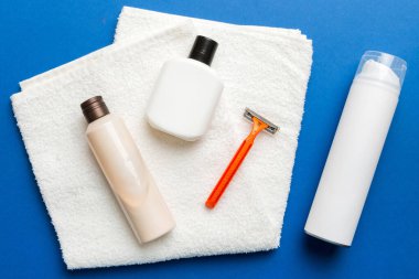 Tıraş Adam seti. Traş makinesi, havlu, losyon ve renkli arka planda tıraş köpüğü. Erkekler banyo aksesuarları üst görünüm.