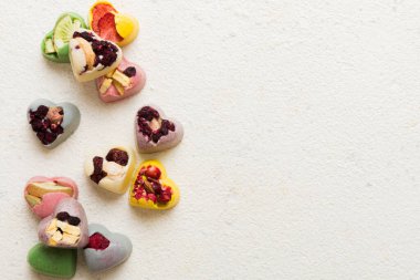 chocolate sweets in the form of a heart with fruits and nuts on a colored background. top view with space for text, holiday concept.