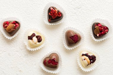 chocolate sweets in the form of a heart with fruits and nuts on a colored background. top view with space for text, holiday concept.
