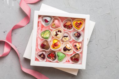 Holiday composition: sweet candy, with gift boxes with bow and chocolate hearts, photo template, background. Top View with copy space on colored background.