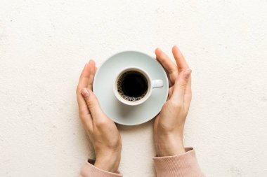 Renkli arka planda bir fincan kahve tutan minimalist stil bir kadın. Düz yerde, kapuçino bardağının üstünde. Metin için boş yer, kopyalama alanı. Kahve bağımlılığı. Üst manzara, düz uzanma.