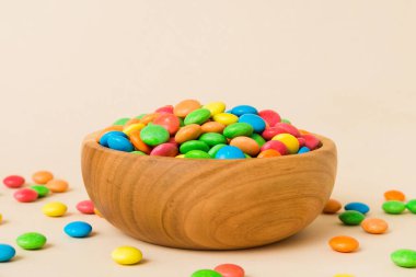 Renkli arka planda bir kasede çok renkli şekerler. Doğum günü ve tatil konsepti. Kopyalama alanı olan üst görünüm.