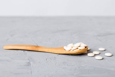 Renkli arka planda bir yığın beyaz hap. Tabletler masaya saçılmış. Kırmızı yumuşak jelatin kapsül yığını. Vitaminler ve beslenme takviyeleri konsepti.