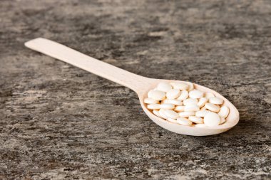 Heap of white pills on colored background. Tablets scattered on a table. Pile of red soft gelatin capsule. Vitamins and dietary supplements concept.