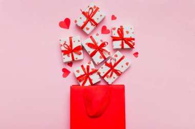 Gift boxes pop out from paper bag top view on colored background. bag packing handmade boxes fall out Concept of holidays, shopping, sale, discounts. Top view, flat lay.