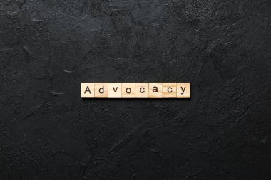 Tahta blokta ADVOCACY kelimesi yazıyor. Desing, konsept için çimento masadaki ADVOCACY metin.