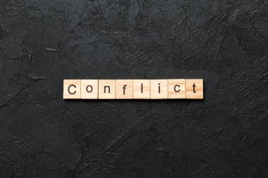 Tahta bloğa yazılmış KONFLICT kelimesi. Deksing, konsept için çimento masadaki CONFLICT metin.