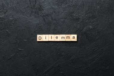 Tahta blokta yazan ikilem kelimesi. Desing, konsept için çimento masanın üzerindeki ikilem metni.