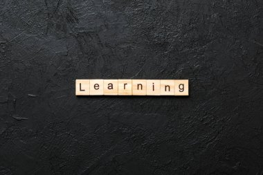 Tahta blokta yazılmış bir kelime. Çimento sehpası üzerindeki ders metni..