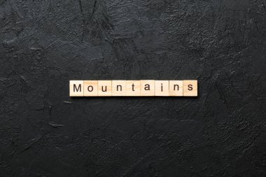 Ahşap bloğa yazılmış bir kelime. Dağlar çimento masa üzerinde metin desing, konsept için.