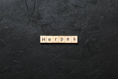 herpes word written on wood block. herpes text on table, concept. clipart