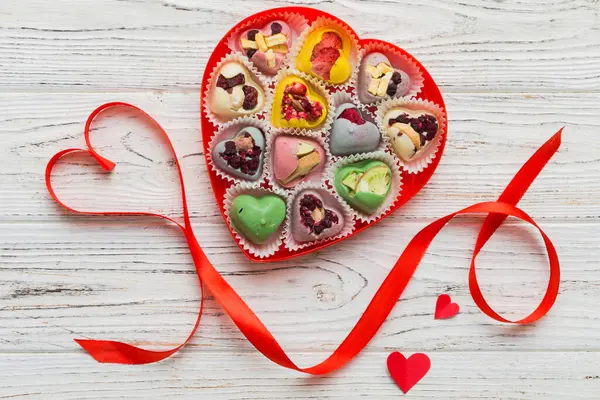 Valentine day composition: sweet candy, with gift boxes with bow and red felt hearts, photo template, background. Top View with copy space.