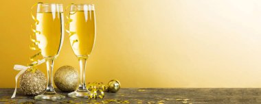Champagne glasses and christmas decor on colored holiday background. Flat lay New Year decorations.