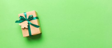 wrapped christmas or other holiday handmade present in paper with colored ribbon. Present box, decoration of gift on colourfull table, top view with copy space.