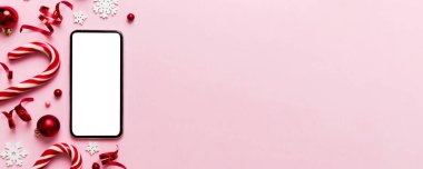 Digital phone mock up with rustic Christmas decorations for app presentation top view with empty space for you design. Christmas online shopping concept. Tablet with copy space on colored background.
