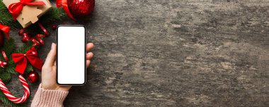 Mesaj atmak için yeri olan bir Noel modeli. Noel reklamı, uygulama şablonu. Masa arkasında boş ekran olan el ele tutuşan telefon. Mutlu yıllar ve Xmas Flat.