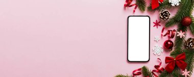 Digital phone mock up with rustic Christmas decorations for app presentation top view with empty space for you design. Christmas online shopping concept. Tablet with copy space on colored background.