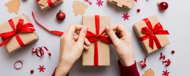 Kadınlar Noel tatili için sürpriz hediyeler hazırlıyor. İş yerinde el aletleri ve manzarayla oturuyor. Renkli masada Noel hediyesini paketleyen kadın..