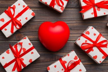 gift box with red bow and red heart on colored background . Top view. Flat lay.
