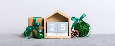 25 december. Christmas composition on colored background with a wooden calendar, with a gift box, toys, bauble copy space.