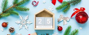 Christmas calendar 25 december. Christmas gift, fir branches, pine cones. Flat lay, top view. New Year decorations on a colored background.