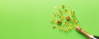Yaratıcı düz kompozisyon, bir şişe şampanya ve renkli arka plan üzerine yazı için yer. Renkli parti flamalarıyla şampanya şişesi. tatil ya da noel konsepti.