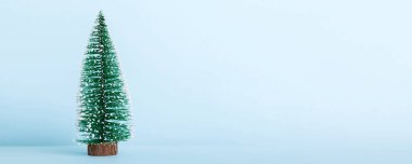 One small Christmas tree on colored background. new year decoration with copy space.