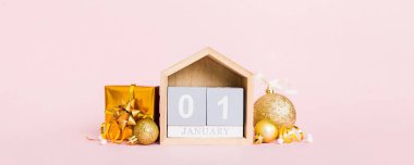 1 january. Christmas composition on colored background with a wooden calendar, with a gift box, toys, bauble copy space.