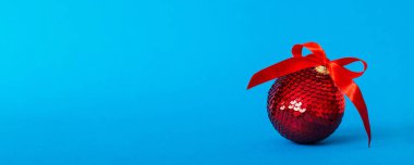 Christmas ball on colored background. decoration bauble with ribbon bow with copy space.