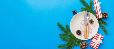 Noel süsleri, tabaklar, inekler, çatallar ve kaşıklarla Noel sofrası. Noel tatili geçmişi. Kopyalama alanı olan üst görünüm.