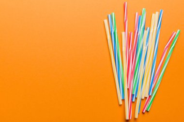 Renkli arka planda renkli plastik pipetler, düz yatış. Metin için Boşluğu Kopyala.