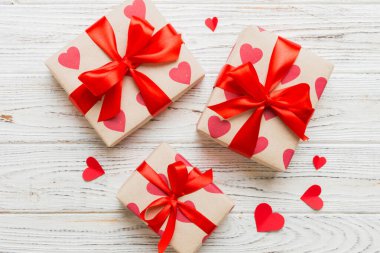 Top view photo of valentine day decorations gift box with red ribbon bow on colored background. Holiday gift boxes with top view.