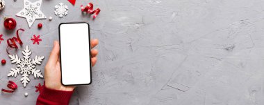 Mesaj atmak için yeri olan bir Noel modeli. Noel reklamı, uygulama şablonu. Masa arkasında boş ekran olan el ele tutuşan telefon. Mutlu yıllar ve Xmas Flat.