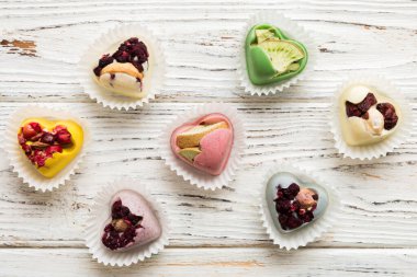 chocolate sweets in the form of a heart with fruits and nuts on a colored background. top view with space for text, holiday concept.