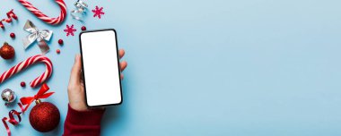 Mesaj atmak için yeri olan bir Noel modeli. Noel reklamı, uygulama şablonu. Masa arkasında boş ekran olan el ele tutuşan telefon. Mutlu yıllar ve Xmas Flat.