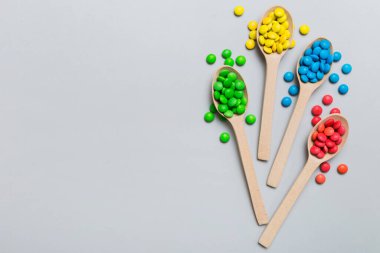 Renkli arka planda kaşık üzerinde renkli tatlı şekerler. Fotokopi alanı ile şekerleme dekoru üst görünümü.
